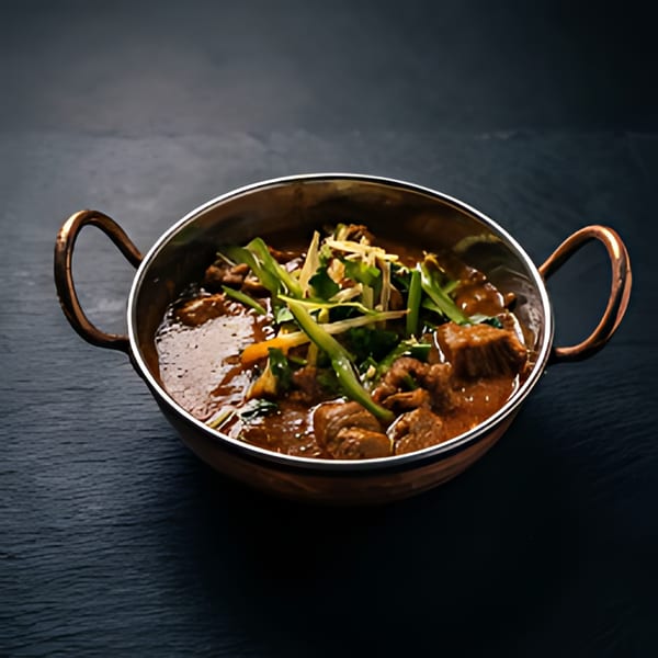 A copper karahi filled with The Kabab House's rich, savory kebab, garnished with fresh herbs.