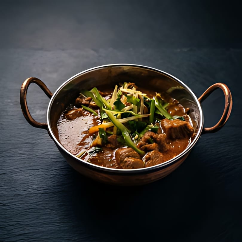 A copper karahi filled with The Kabab House's rich, savory kebab, garnished with fresh herbs.