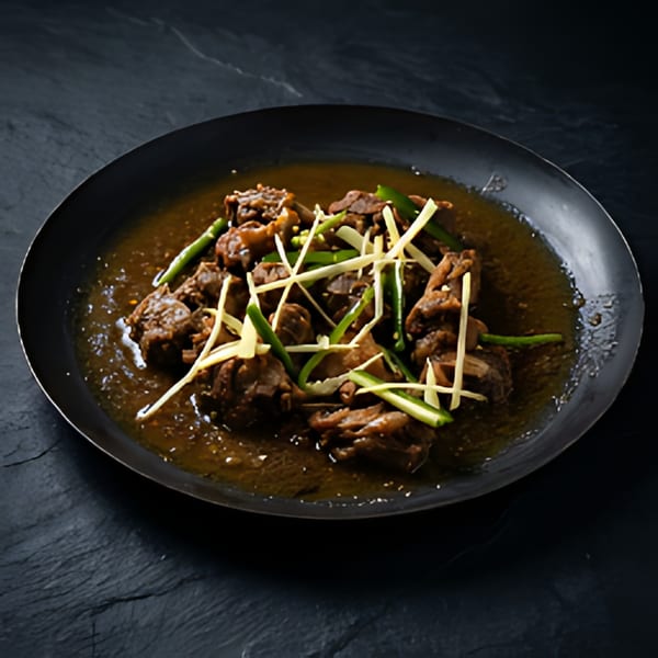 A dark metal pan filled with The Kabab House's rich, brown stew, garnished with green chilies and ginger.